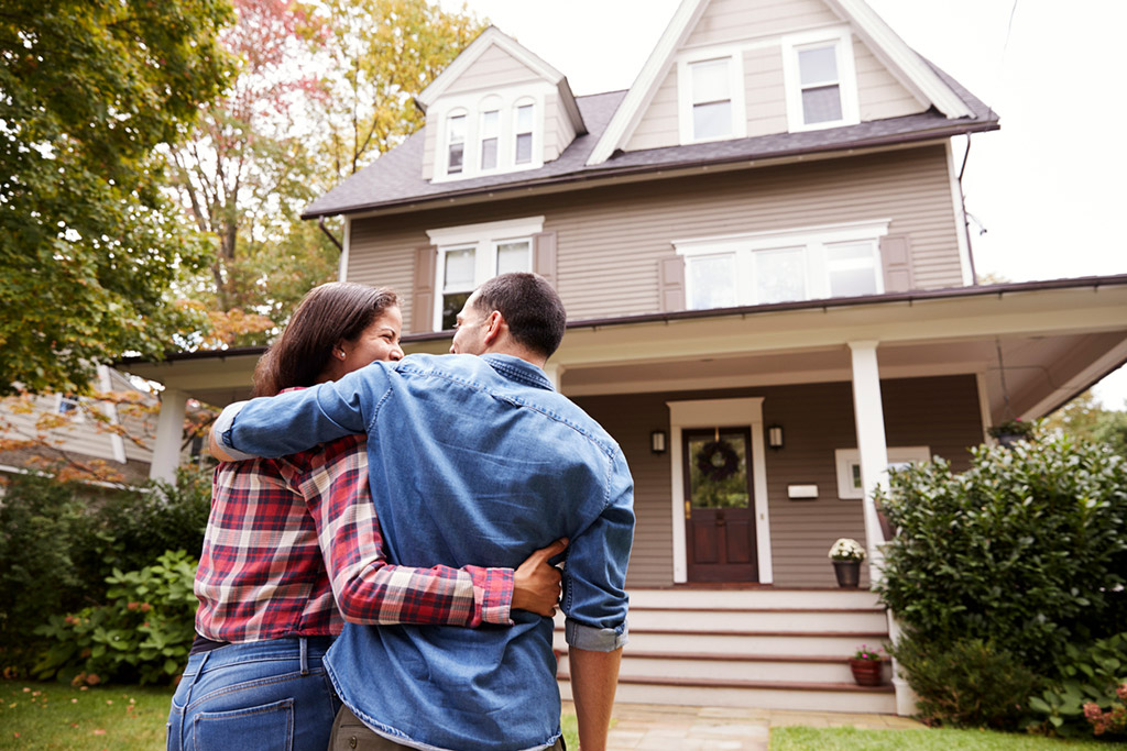 happy couple infront of new house