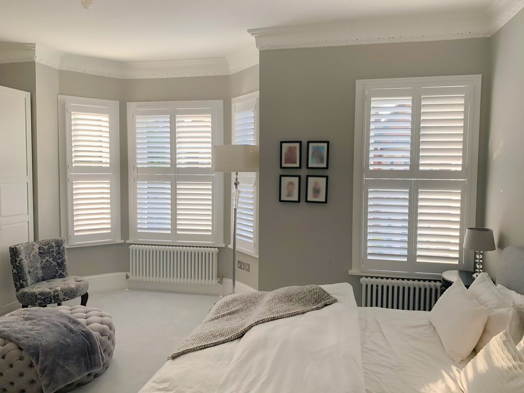 Bay window tier on tier white shutters in bedroom
