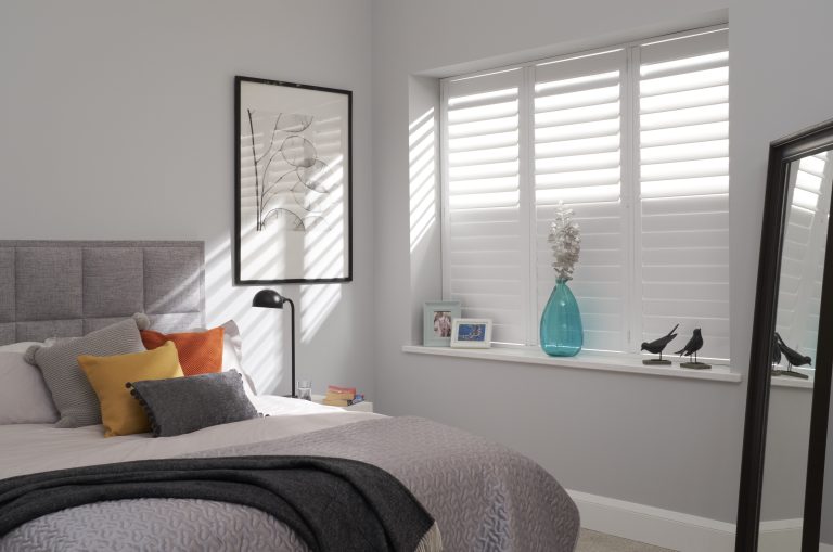 Modern bedroom with white window shutters showing how light and insulation can be controlled